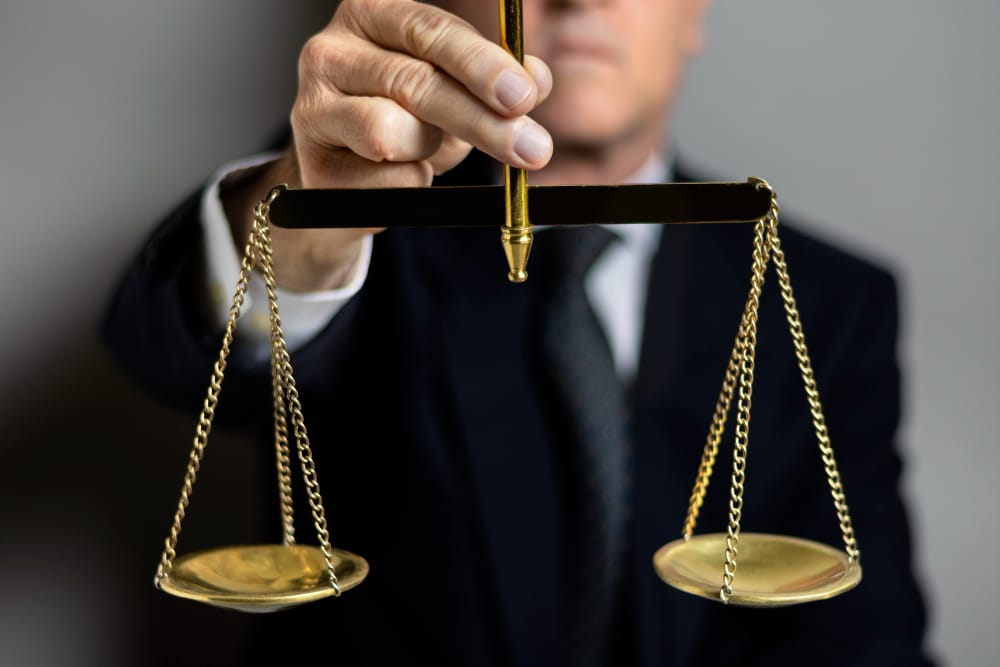 A person in a suit holding a set of brass scales of justice